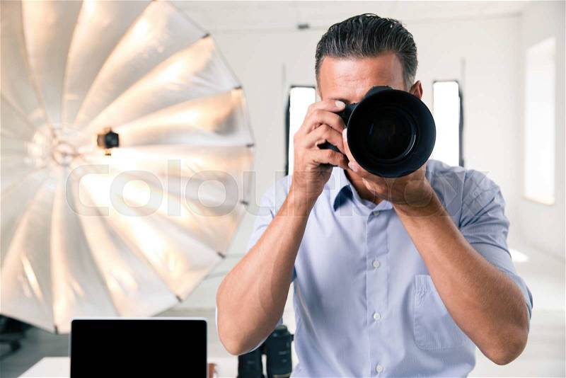 Photographer making photo on camera in studio, stock photo