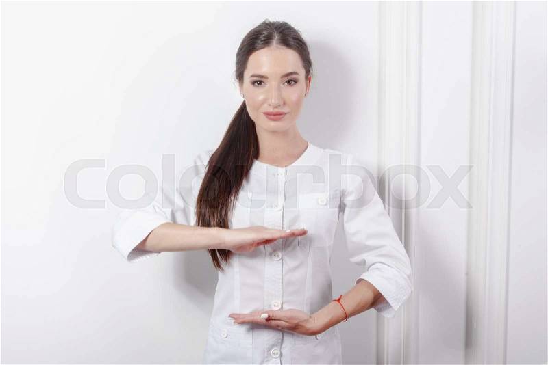 Young doctor with holding pose on white clinic background, stock photo