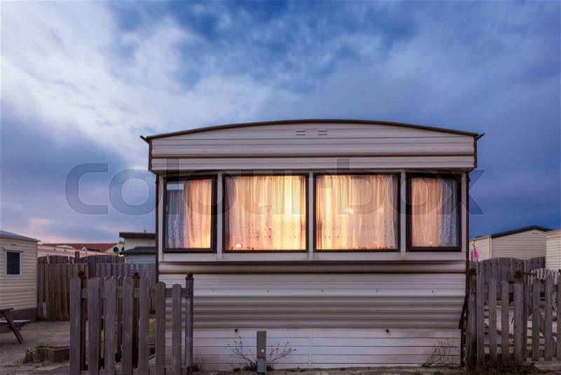 Old vacation home trailer illuminated at dusk. Trailer park in Holland, Netherlands, stock photo