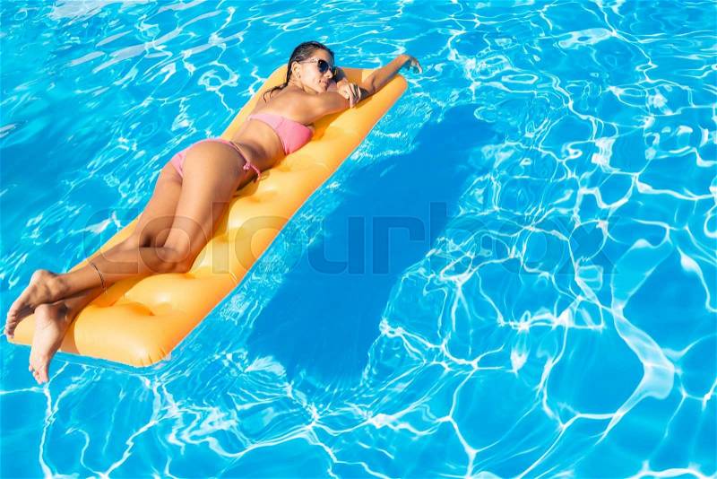 Woman lying on air mattress in the swimming pool , stock photo