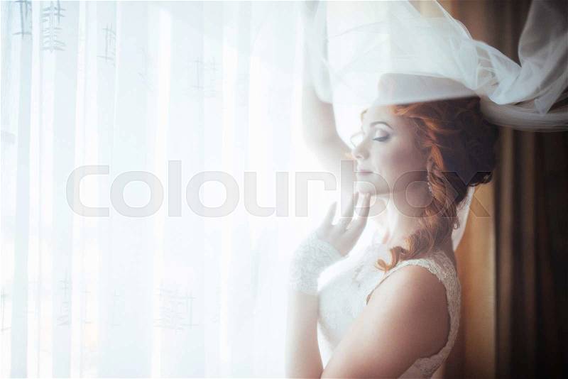 The girl stands up for a curtain at a window, stock photo