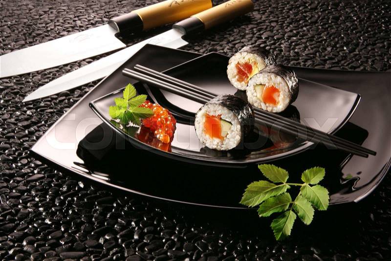 Typical Japanese food with knives on a black plate, stock photo