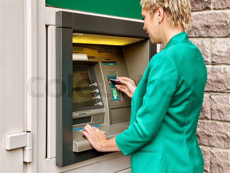 Business woman operates an ATM on the street, stock photo