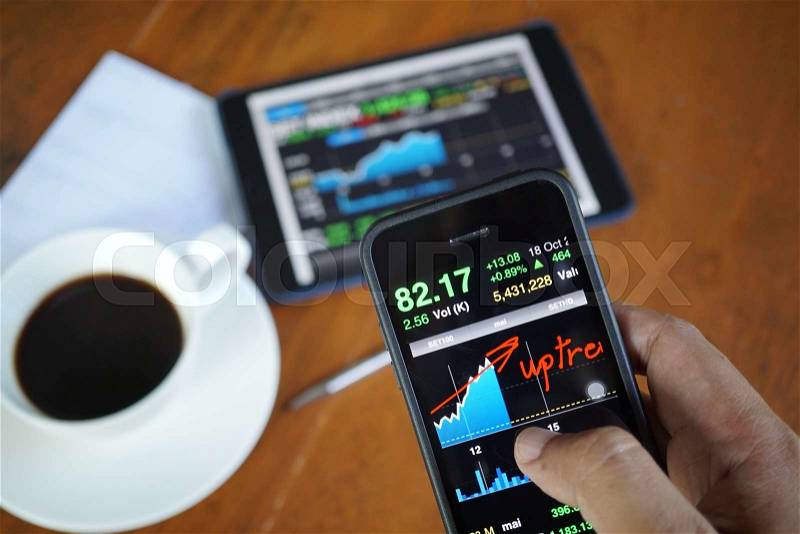 Business man hand hold and touch screen on smart phone,tablet,cellphone over blur tablet chart market and coffee background, stock photo