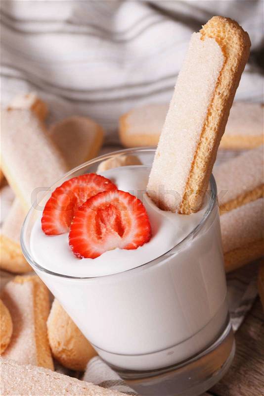 Tasty cookies Savoiardi and whipped cream with strawberries in a glass closeup. vertical\, stock photo