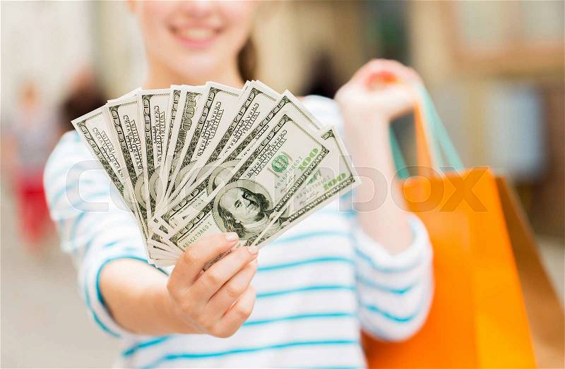 Tourism, travel, sale and consumerism concept - close up of happy woman with shopping bags and dollar money on city street, stock photo