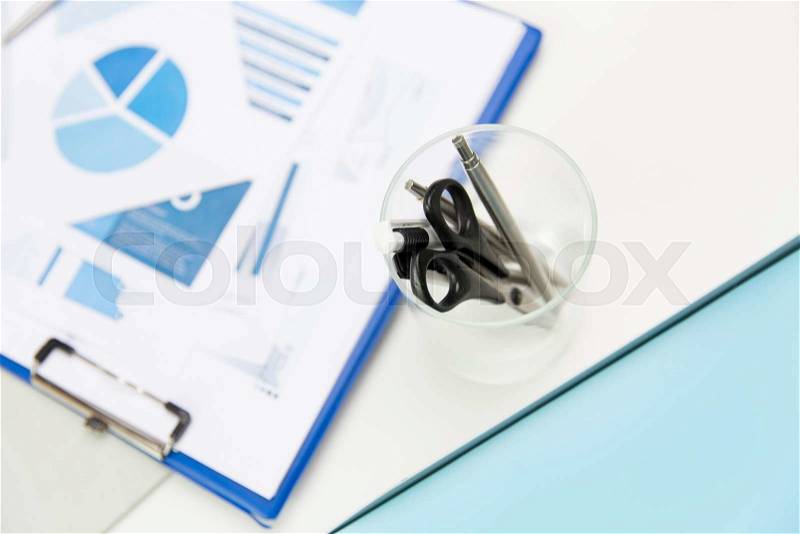 Business, stationery and office supply concept - close up of organizer with scissors and pens over charts on table, stock photo
