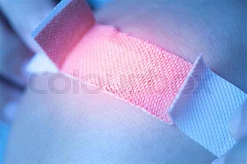 Applying adhesive bandage on knee, stock photo