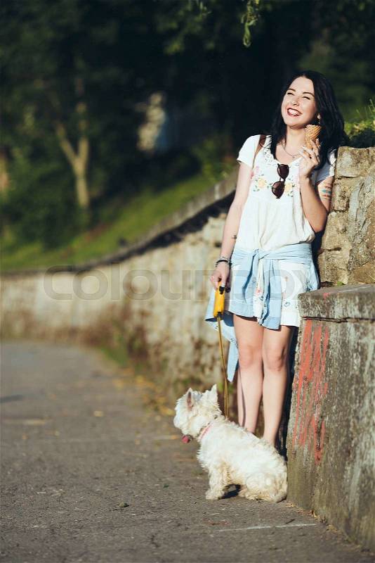 Girl with ice cream and dog against the wall, stock photo