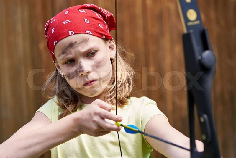 Girl archer with bow shooting to sport aim in sunny summer day, stock photo