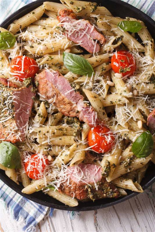 Penne pasta with meat, tomato and pesto close up on a plate. vertical view from above\, stock photo