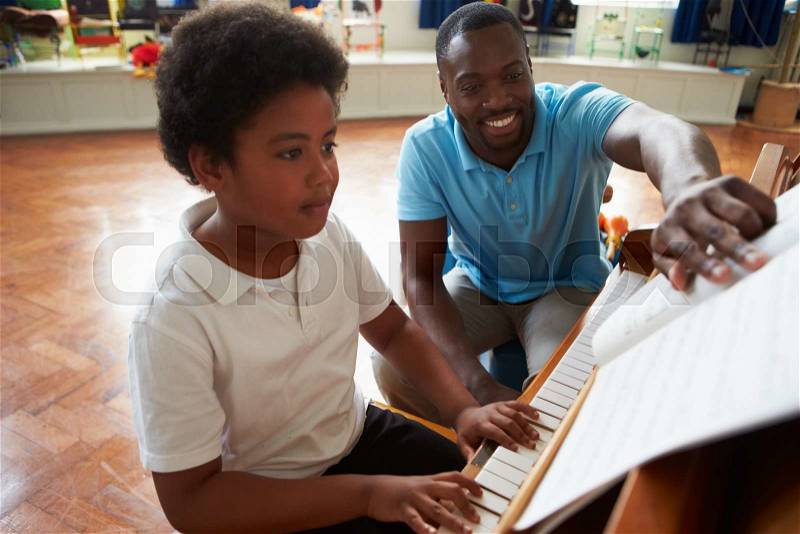 Male Student Enjoying Piano Lesson With Teacher, stock photo
