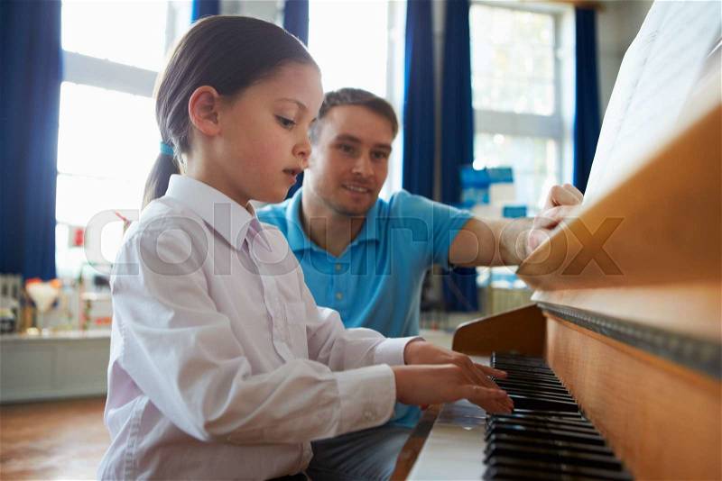 Female Student Enjoying Piano Lesson With Teacher, stock photo