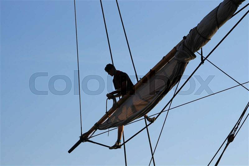 One of the crew of the tallship is busy with the sail and ropes during Sail Amsterdam 2015, stock photo