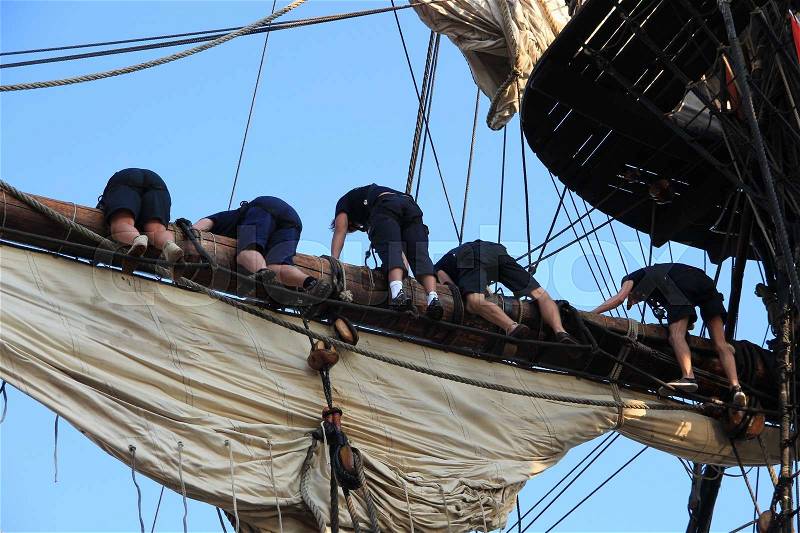 The crew is busy with the ropes and the sails at the tallship during Sail Amsterdam 2015, stock photo