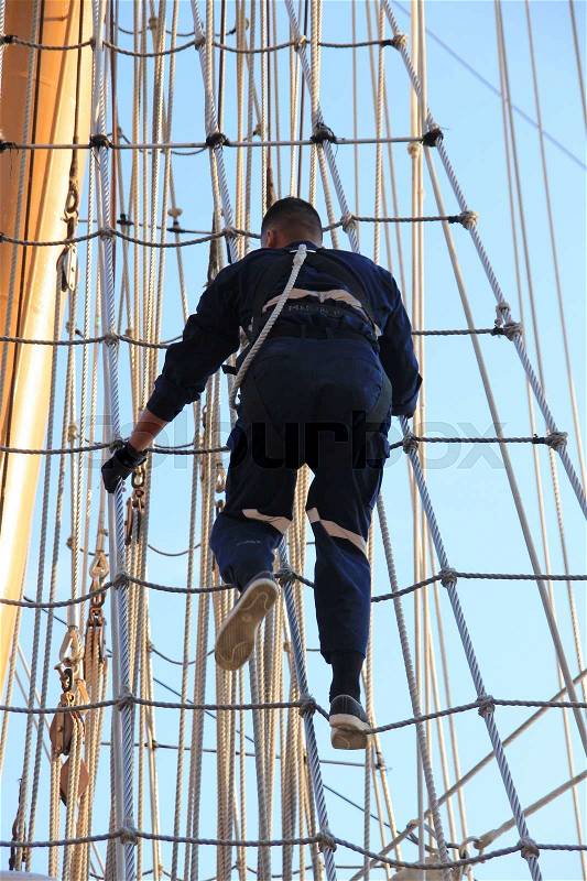 One of the crew goes up in the ropes at the tallship during Sail Amsterdam 2015, stock photo