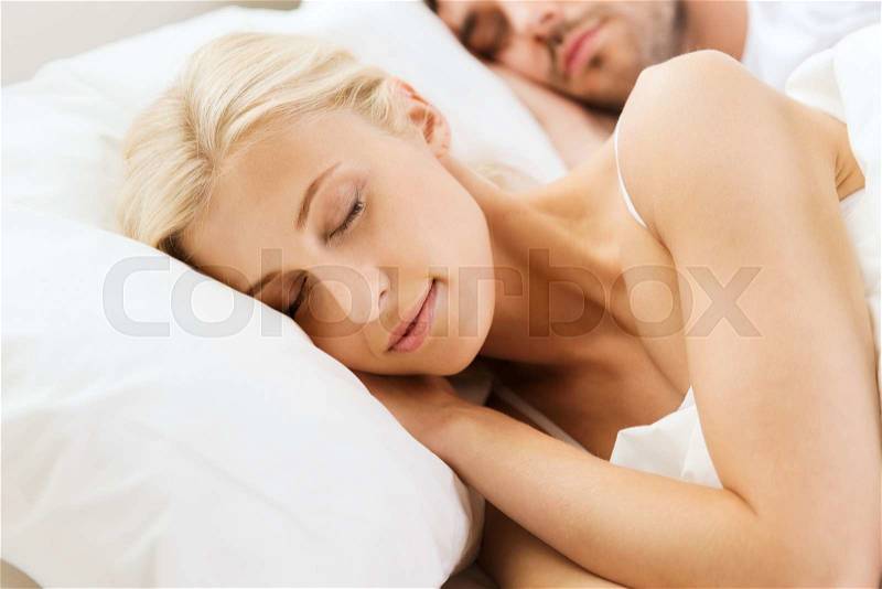 People, rest, relationships and happiness concept - happy woman and man sleeping in bed at home, stock photo