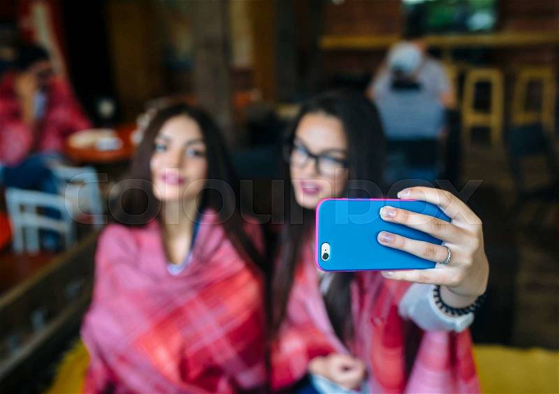 Two close girlfriends want to make a selfie in the cafe on memory, stock photo