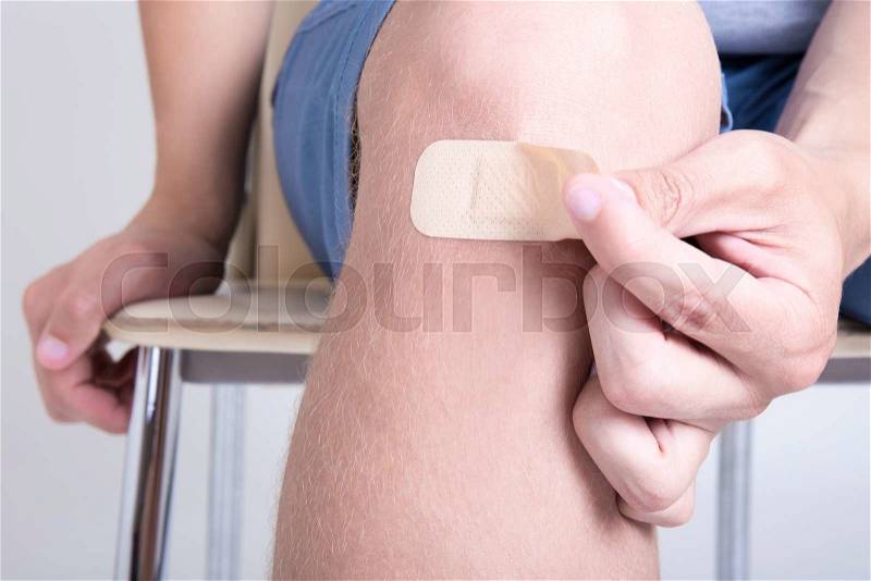 Close up of brown adhesive medical patch on male knee, stock photo
