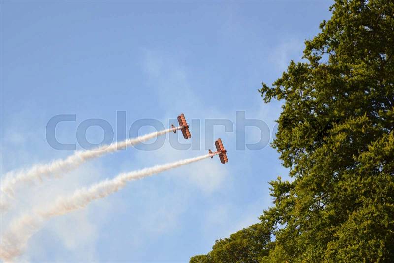 Air show with vintage planes drawing white lines of smoke in the blue sky, stock photo