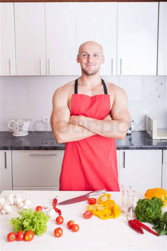 Muscle man cooking in the kitchen, stock photo
