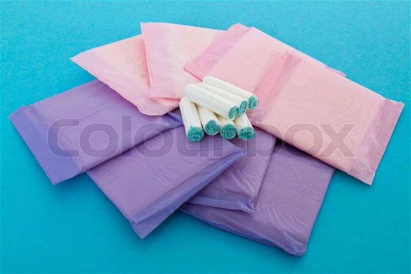 Sanitary napkins and tampons on blue background, stock photo
