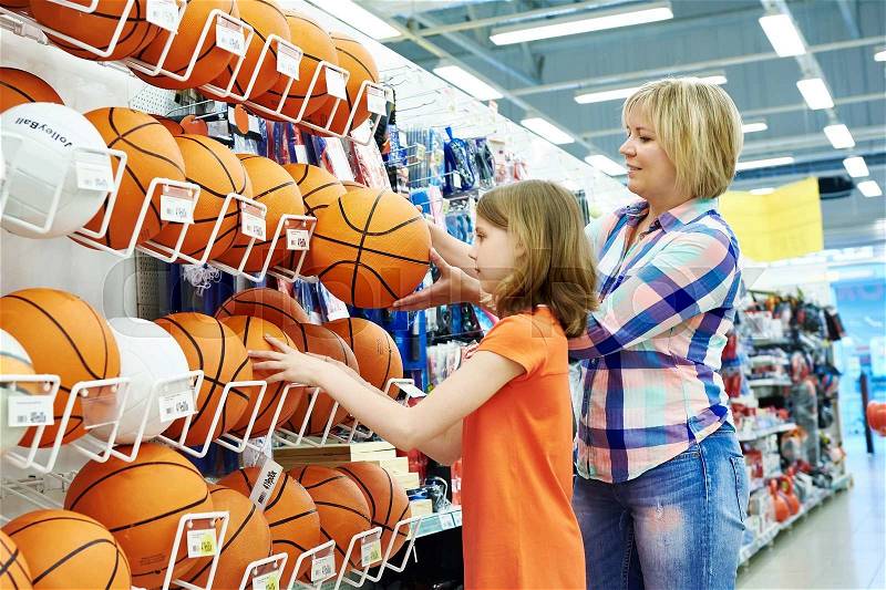 Mother and daughter shopping basketball ball in sport shop, stock photo