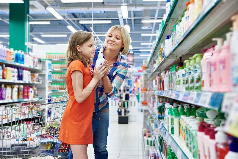 Mother and daughter sniff fragrance shampoo in supermarket, stock photo