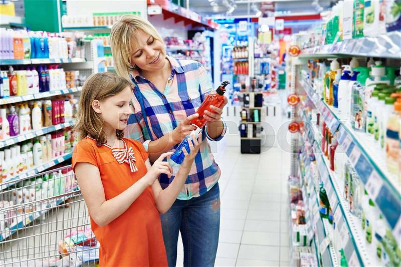 Mother and daughter shopping shampoo in supermarket, stock photo