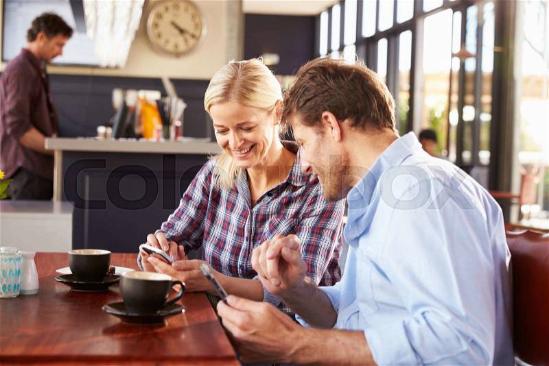 Man and woman using smart phones at coffee shop, stock photo
