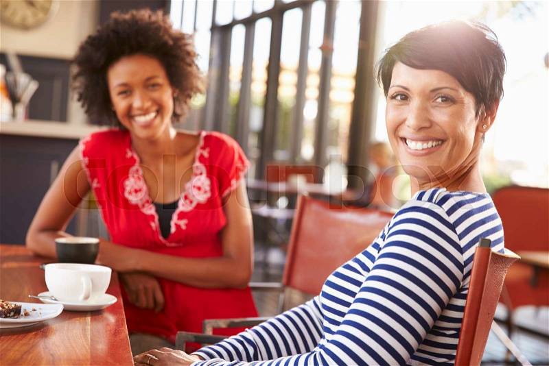 Two female friends meeting at a coffee shop, stock photo
