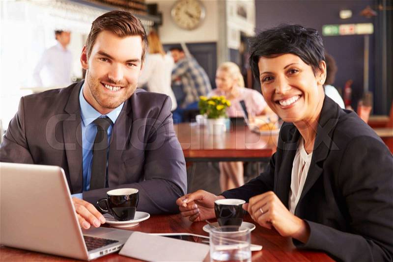 Two business people with laptop meeting in a coffee shop, stock photo