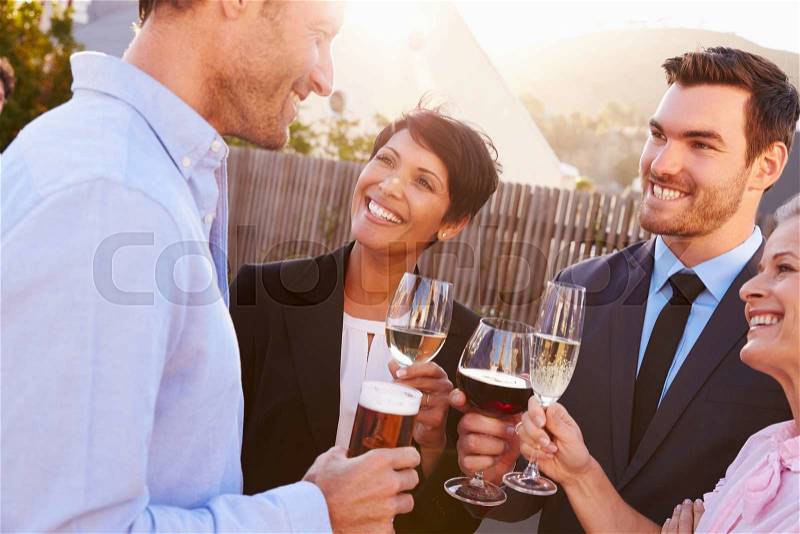 Colleagues drinking after work at a rooftop bar, stock photo