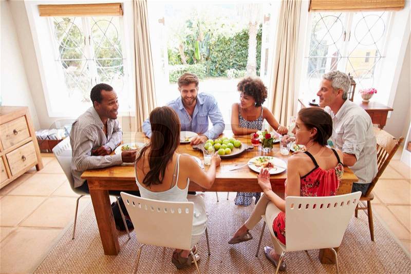 Friends sitting at a table talking during a dinner party, stock photo