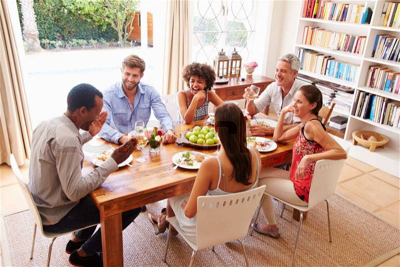 Friends sitting at a table talking during a dinner party, stock photo