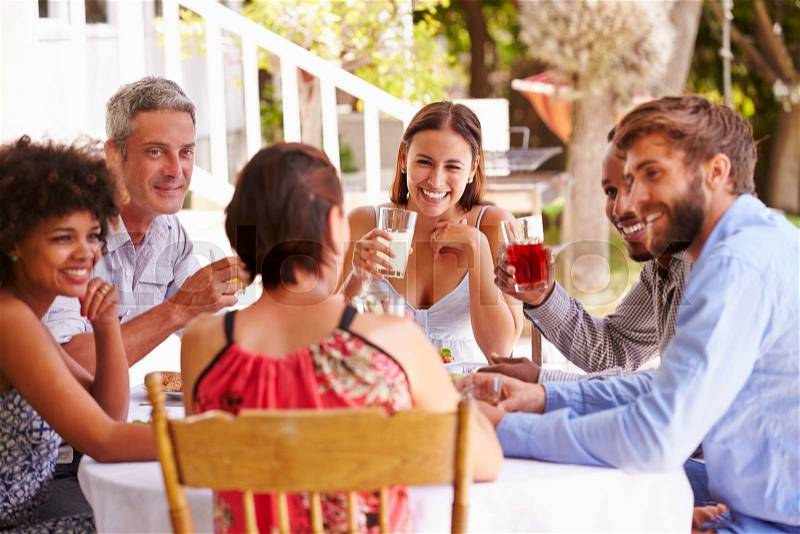 Friends dining together at a table in a garden, stock photo