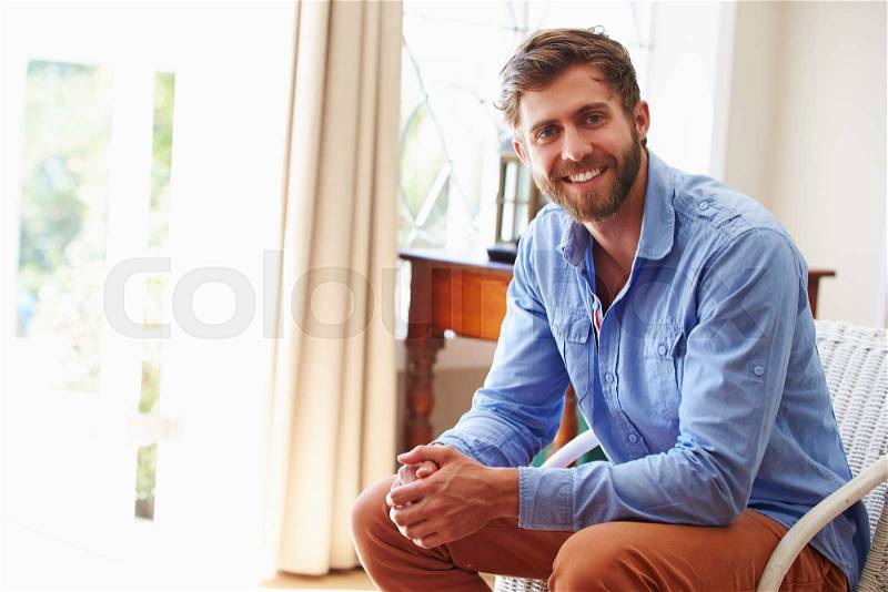 Portrait ofÿa smiling young man sitting in a room, stock photo