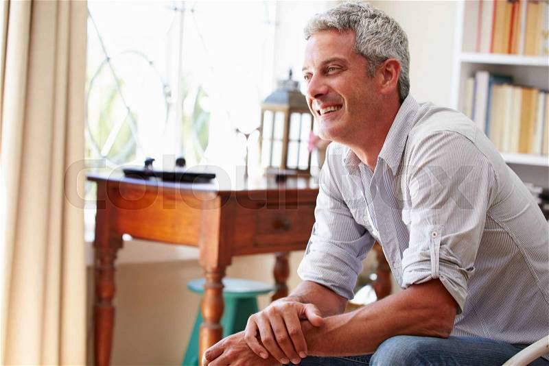 Portrait ofÿa smiling grey haired man sitting in a room, stock photo