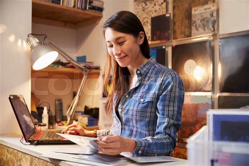 Young woman working behind the counter at a record shop, stock photo