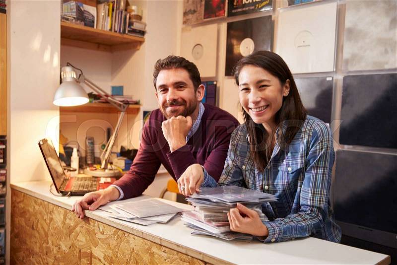 Man and woman working behind the counter at a record shop, stock photo