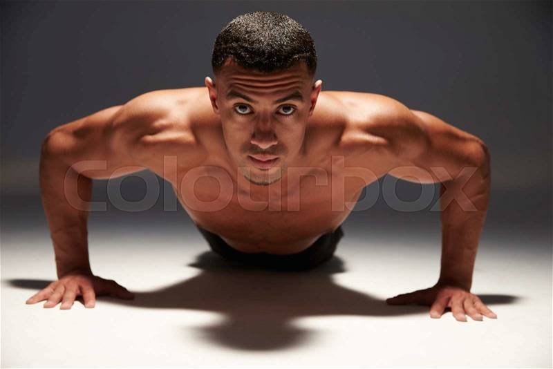 Muscular, shirtless young man doing press-ups, stock photo