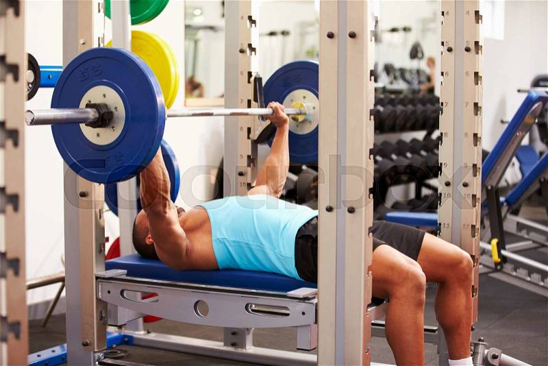 Young man bench pressing weights at a gym, side view, stock photo