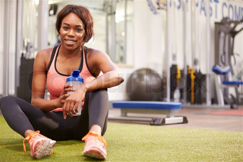 Young woman drinking water in a gym, with copy space, stock photo