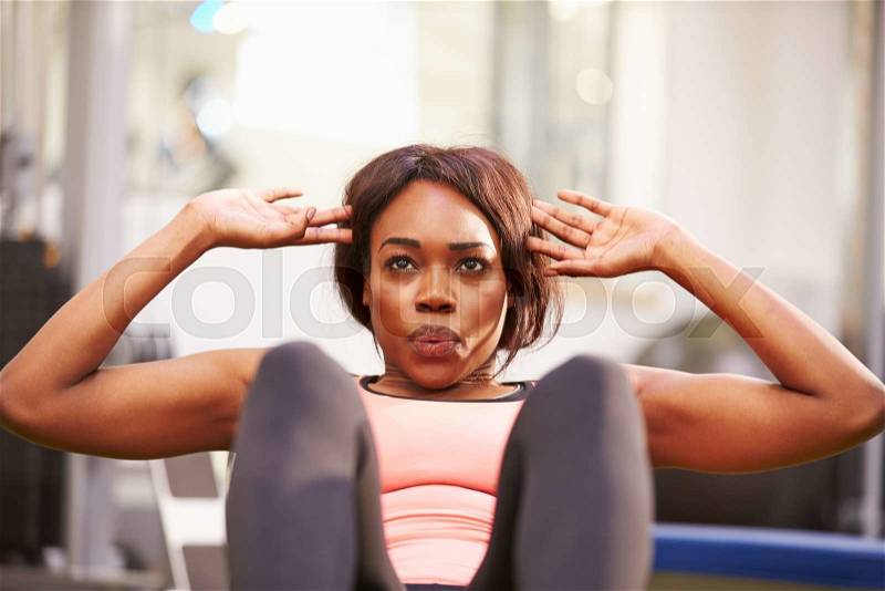 Young woman doing crunches in a gym, close up, stock photo