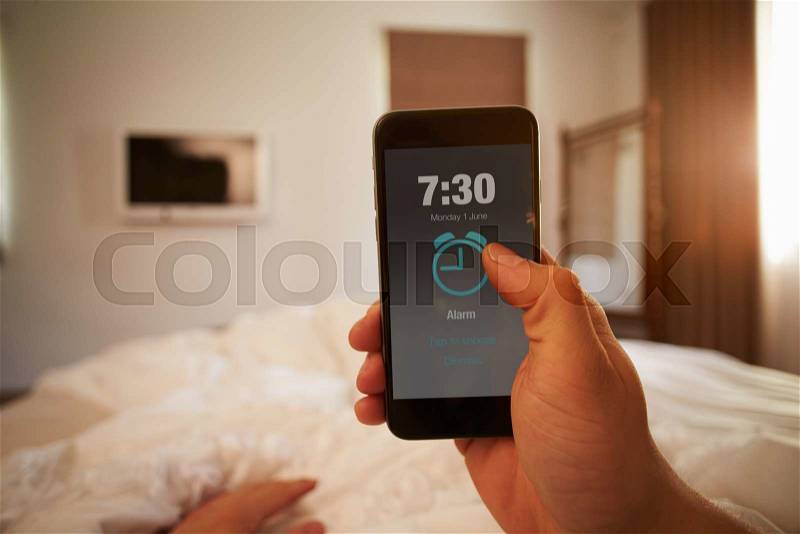 Point Of View Image Of Person In Bed Turning Off Phone Alarm, stock photo