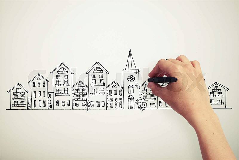 Female hand drawing houses on a paper, stock photo