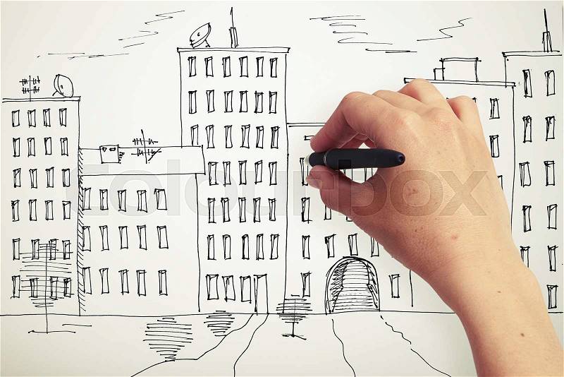 Womans hand drawing houses on a paper, stock photo