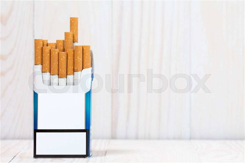 Pack of cigarettes on white wood background. With copy-space for text, stock photo