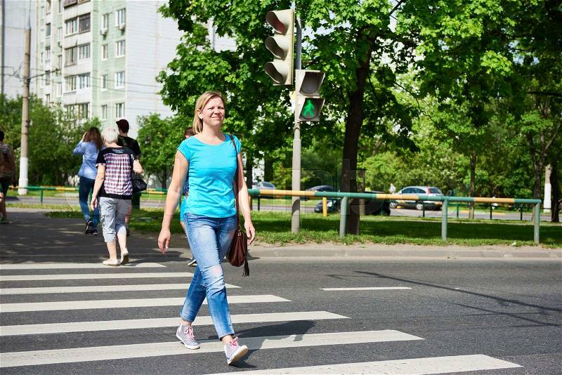 Young woman crossing the road at the green light , stock photo