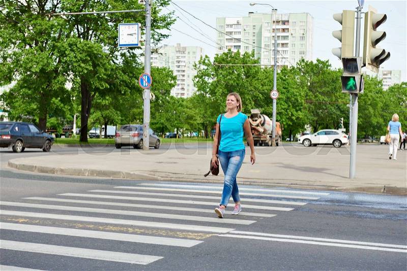 Young woman crossing the road at the green light, stock photo